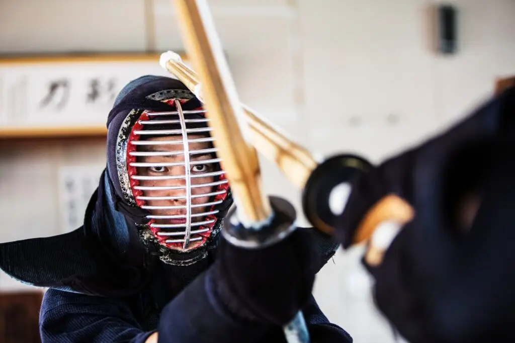 Close up of Japanese Kendo fighter wearing Kendo mask in combat pose.